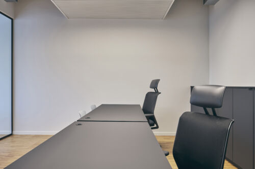 Een vergaderruimte met een zwarte tafel en stoelen.