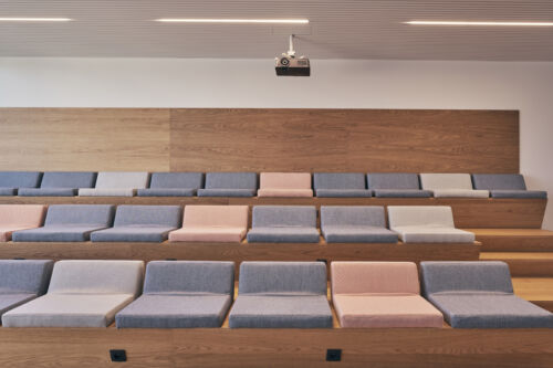 Een auditorium met blauwe en roze stoelen.