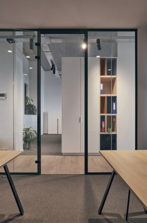 Een kantoor met glazen wanden en houten tafels.