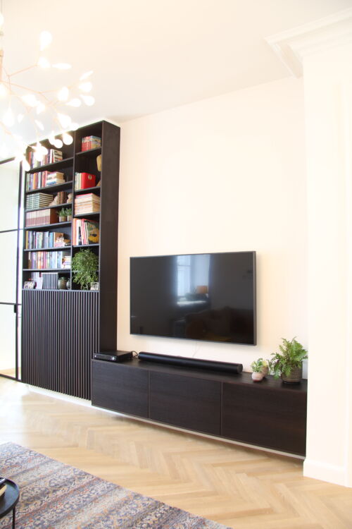 Gezellige woonkamer met tv en boekenplanken.