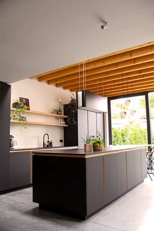 Open keuken met aandacht voor zwarte tinten en een houten plafond.