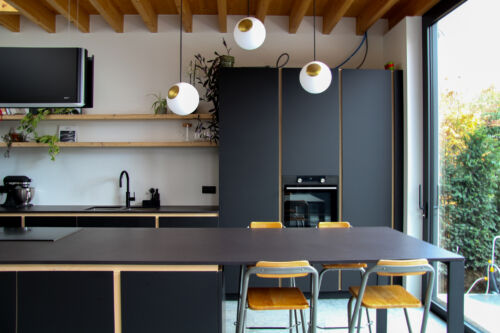 Open keuken met aandacht voor zwarte tinten en een houten plafond.